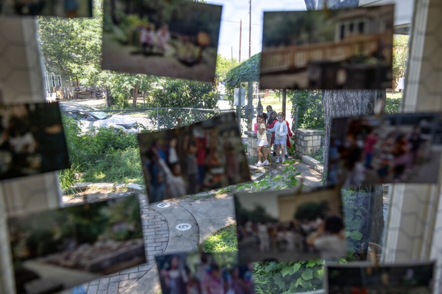 Students are seen through a window walking into a garden. Hanging on the window are old photos which frame the children outside.