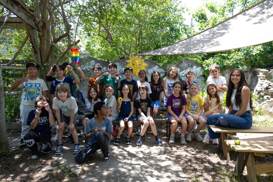 Elementary children and an adult pose for a photo outside.