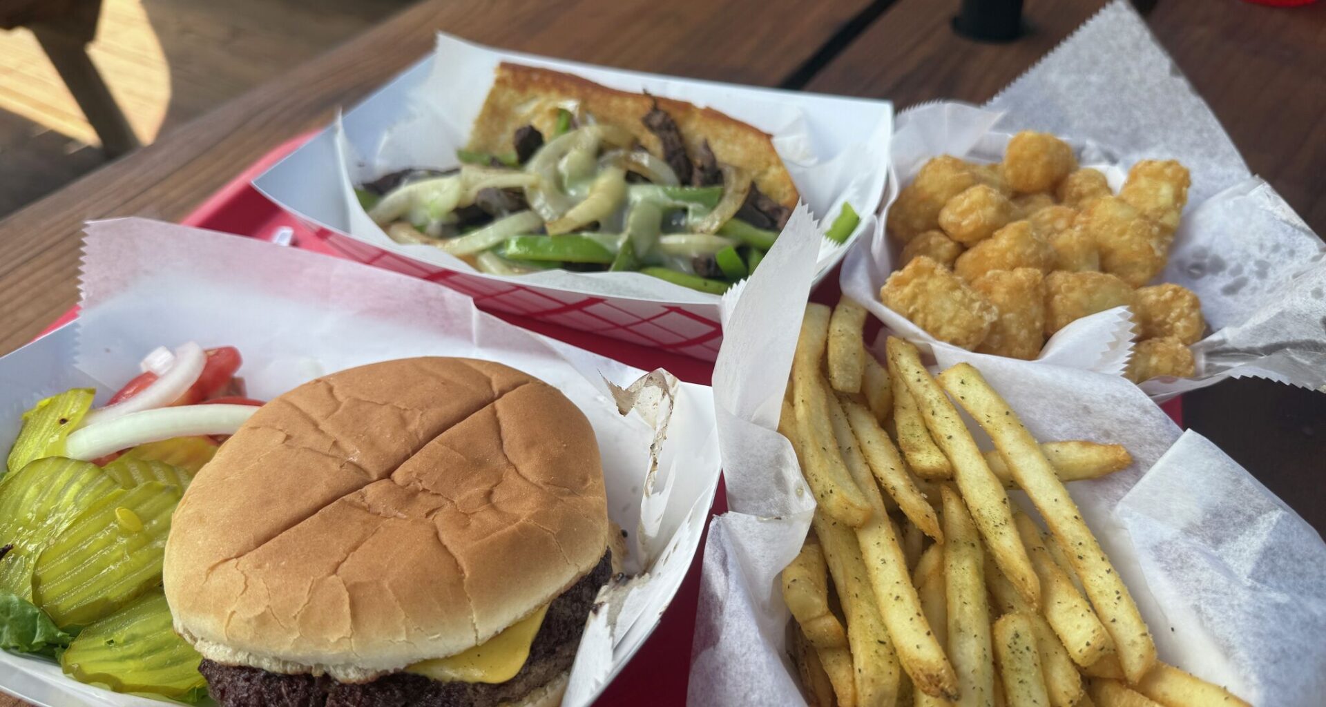 A spread featuring a cheeseburger, Texas cheesesteak, fries and tater tots at Lone Star Float House &amp; Grill on May 16, 2026 in New Braunfels, Texas.
