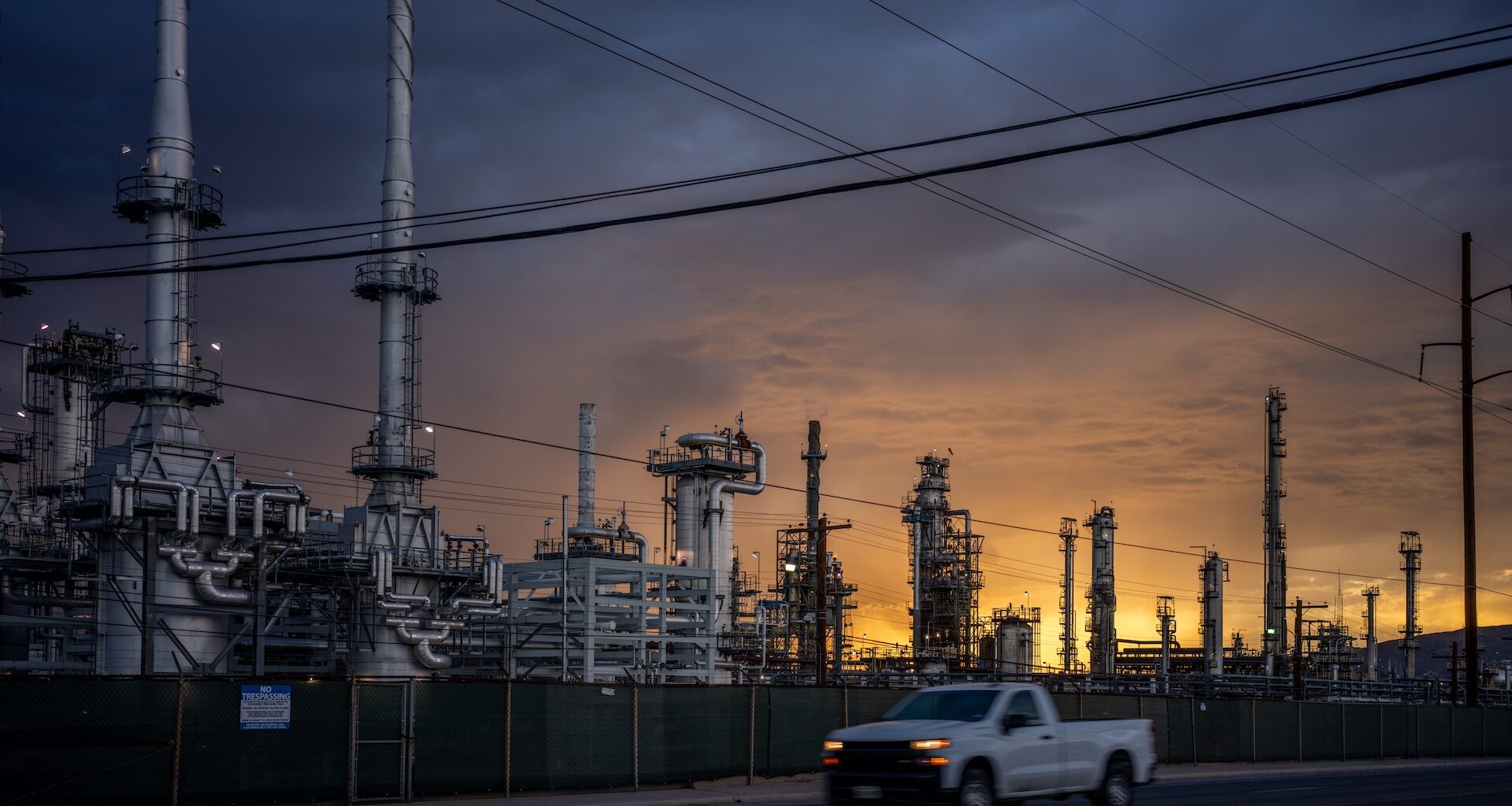 An industrial complex with tall structures and pipes against a sunset sky.