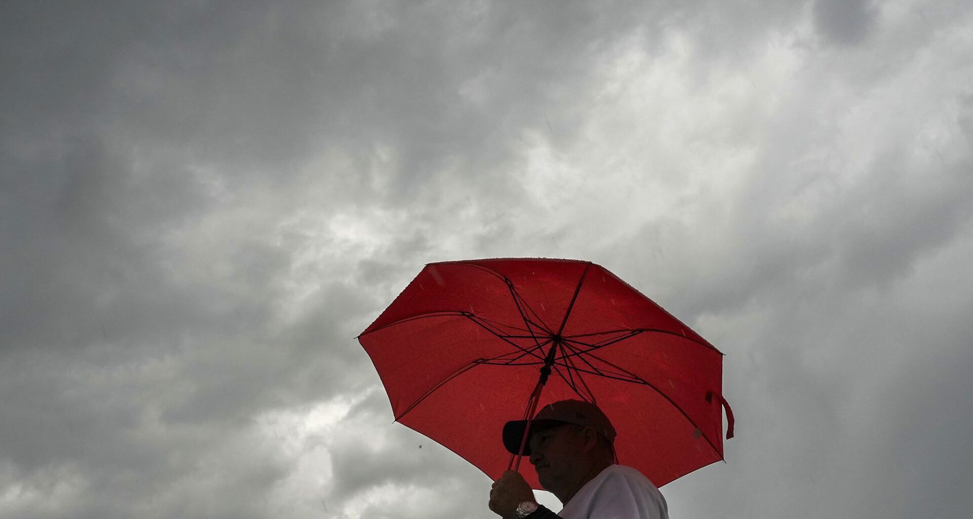 Fans head for the stadium in a heavy rain before a baseball game between the Texas Rangers and the Houston Astros at Globe Life Field  on Monday, May 25, 2026, in Arlington.