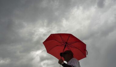 Fans head for the stadium in a heavy rain before a baseball game between the Texas Rangers and the Houston Astros at Globe Life Field  on Monday, May 25, 2026, in Arlington.