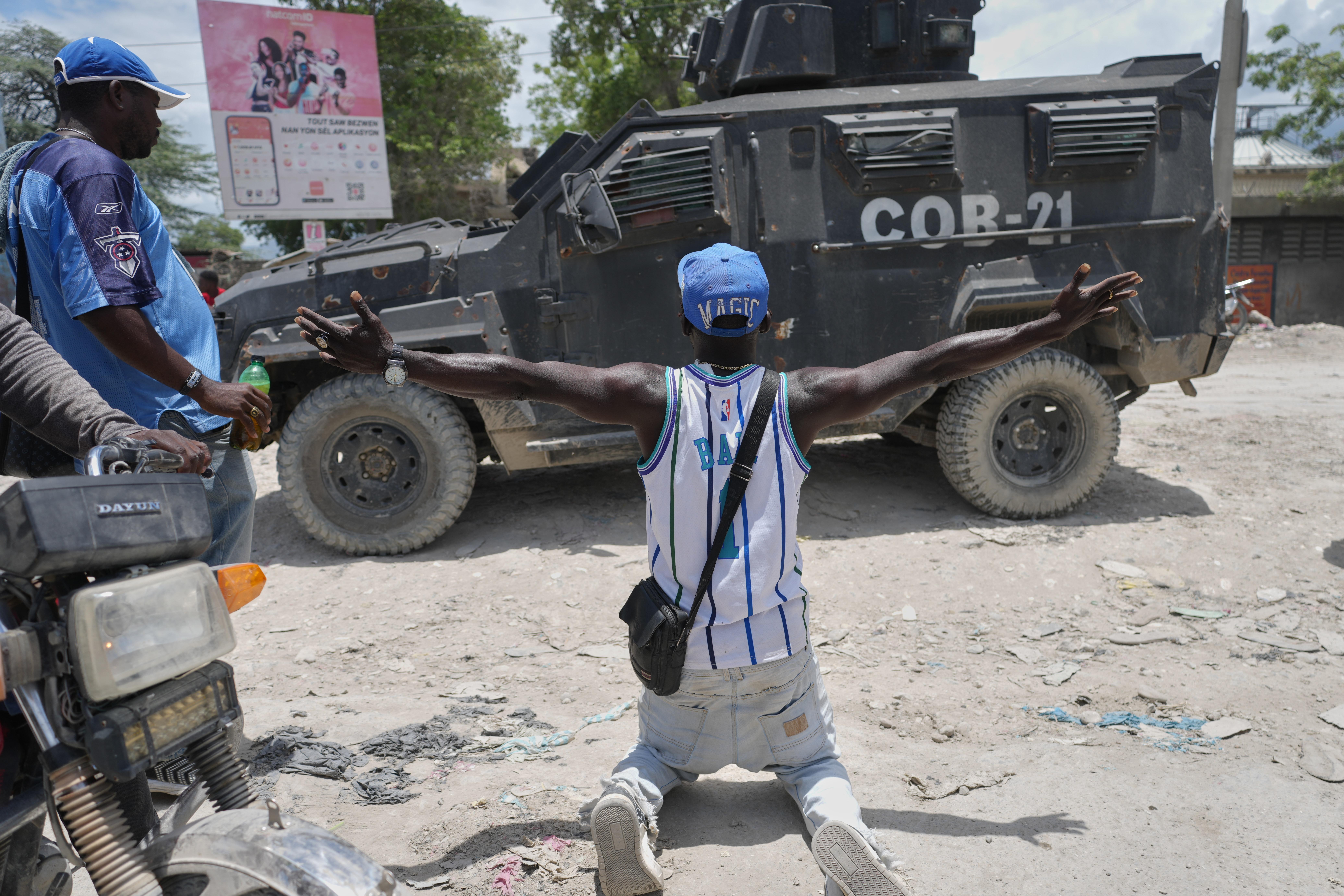 A resident of Cité Soleil kneels before a police armored...