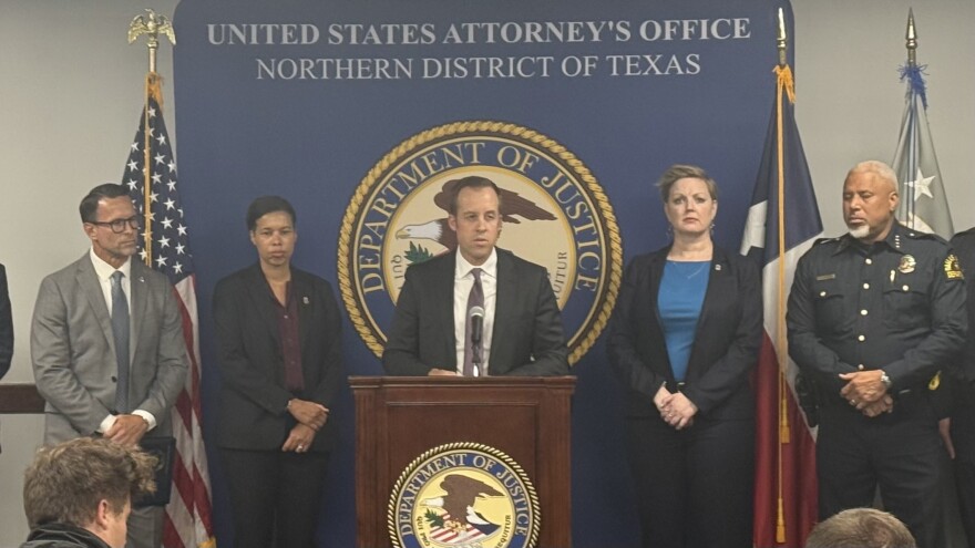 A man speaking in front of a Department of Justice podium