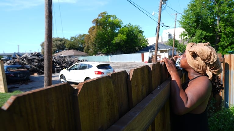 Trish Thompson looks over a fence at the damage left...