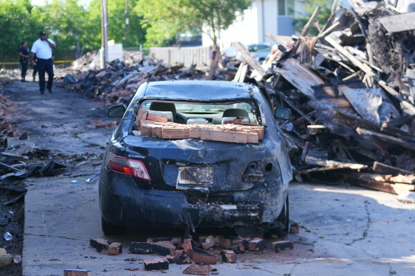 A vehicle is seen damaged following an apartment complex fire, Friday, May 29, 2026, in Dallas. (AP Photo/Julio Cortez)