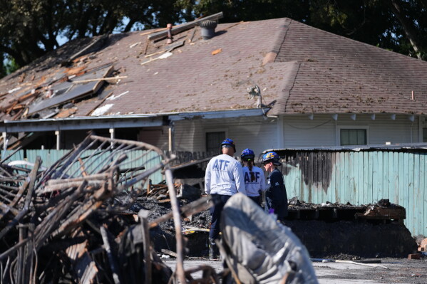 Officials stand near rubble following an apartment complex fire, Friday, May 29, 2026, in Dallas. (AP Photo/Julio Cortez)