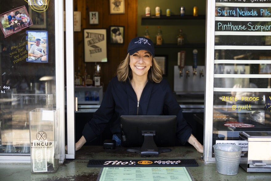 A woman poses for a photo looking through an opening at a service counter.