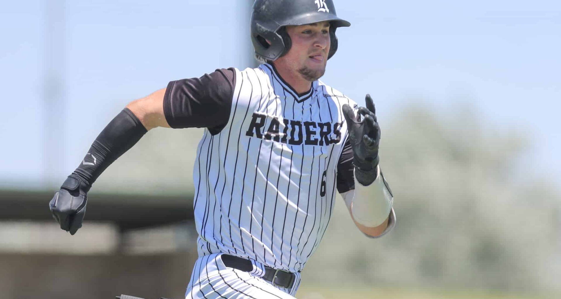Baseball player in a white pinstripe uniform runs on the field, wearing a black batting helmet and gloves.