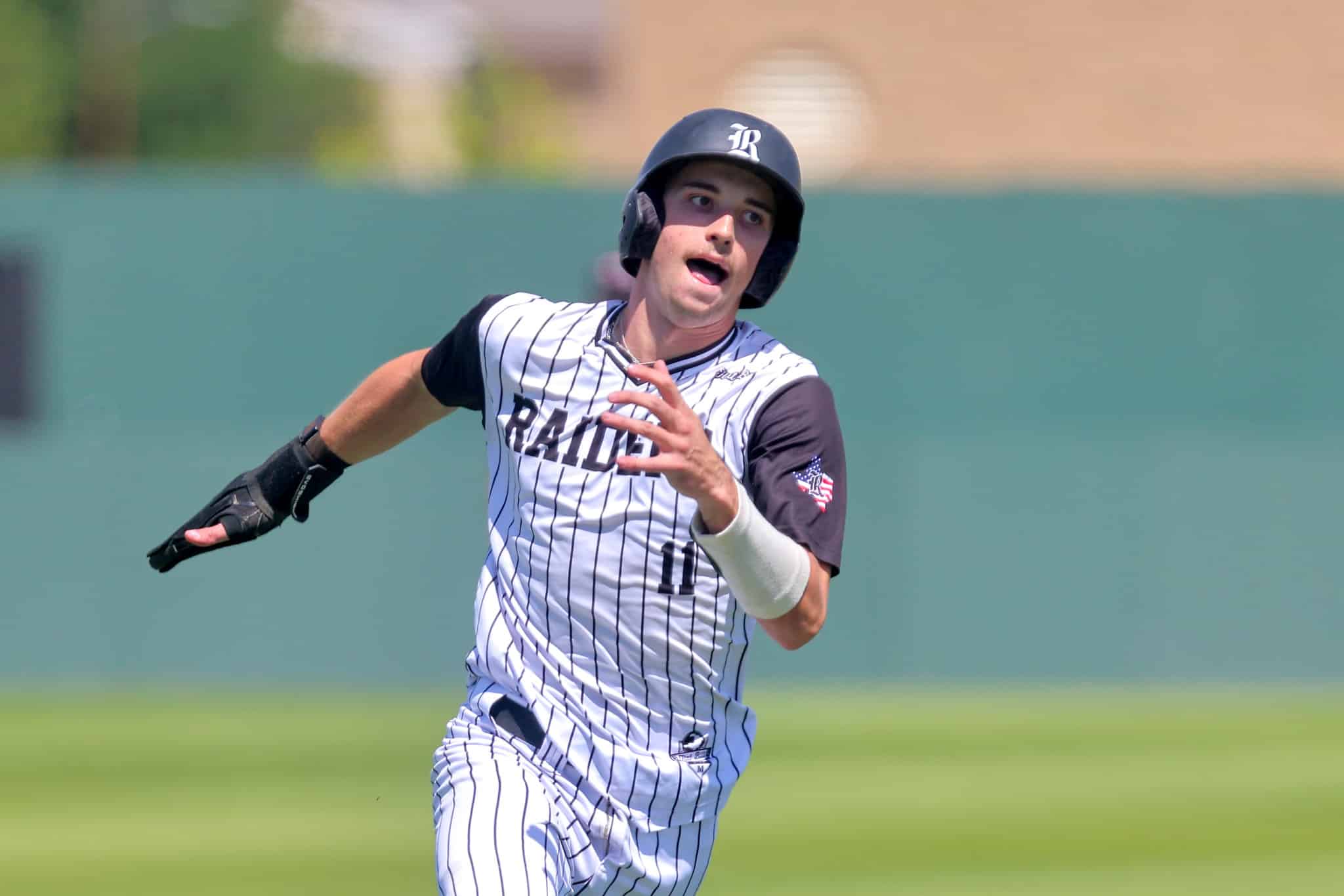 Baseball player in pinstriped uniform and helmet running on a field, glove visible on left hand