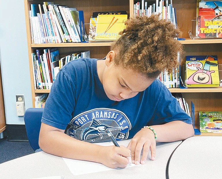 H.G. Olsen Elementary School fourth-grader Kamilla Jenkins works on a poem in the school library on Tuesday, May 19. Staff photo by Jimmy Willden