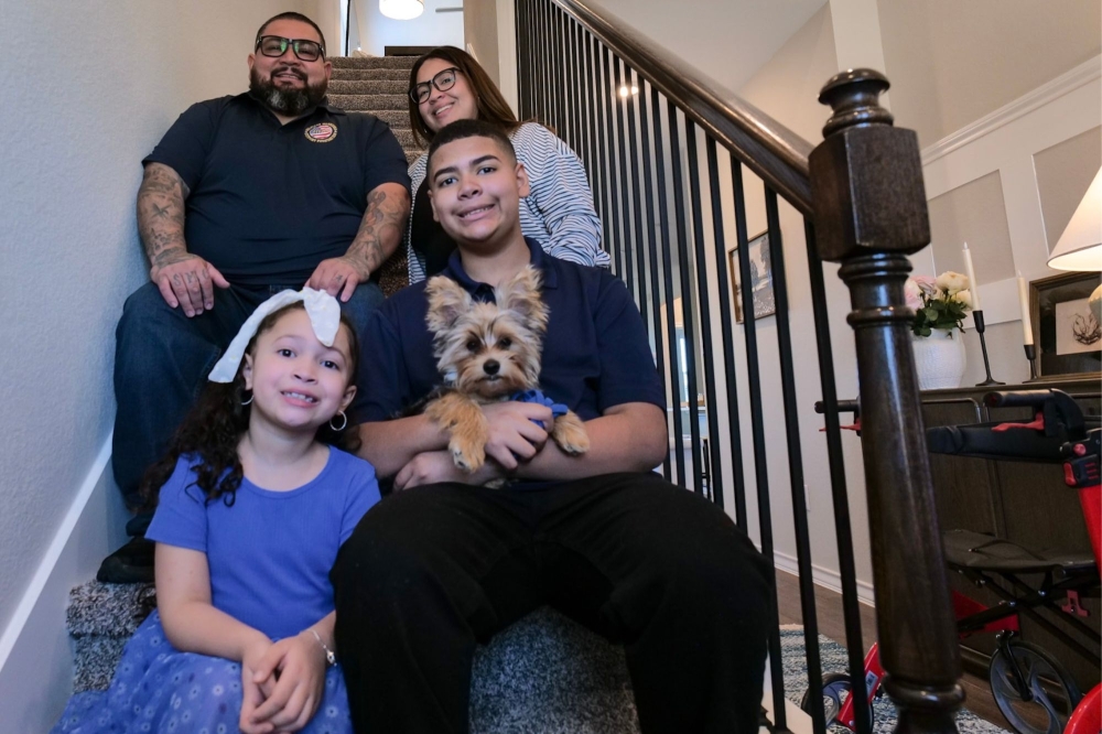 U.S. Marine veteran Luis Valdez sits on the staircase at his family's new home with his wife, two children and the family dog, Charlie. (Courtesy Homes4WoundedHeroes)