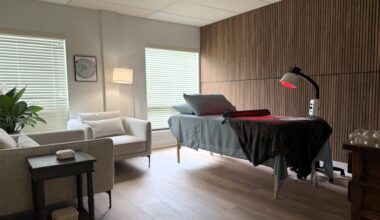 Treatment room with patient bed and red light, along with two arm chairs.