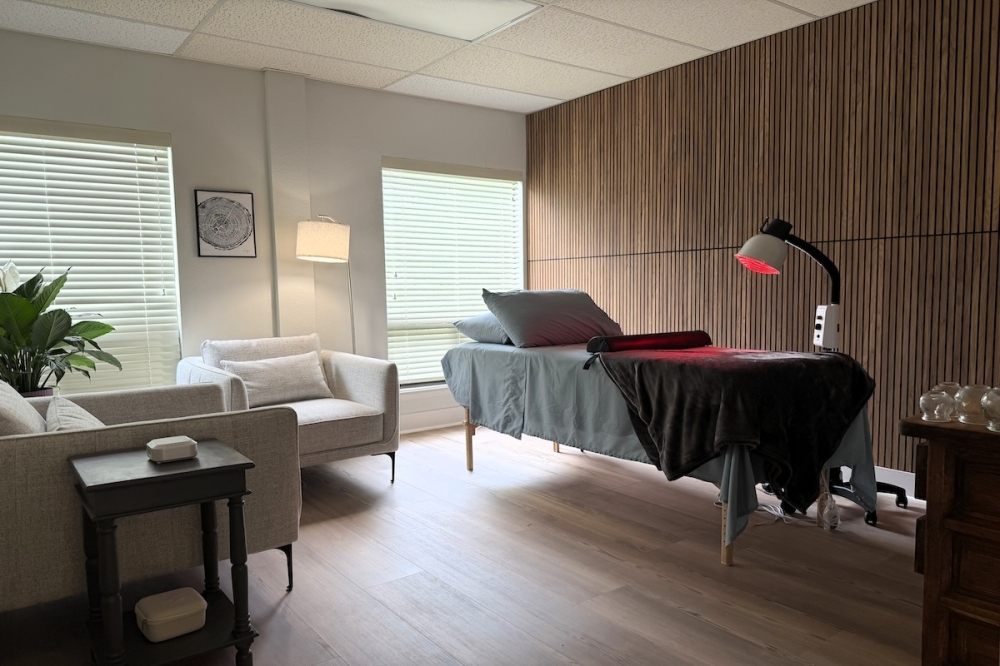 Treatment room with patient bed and red light, along with two arm chairs.