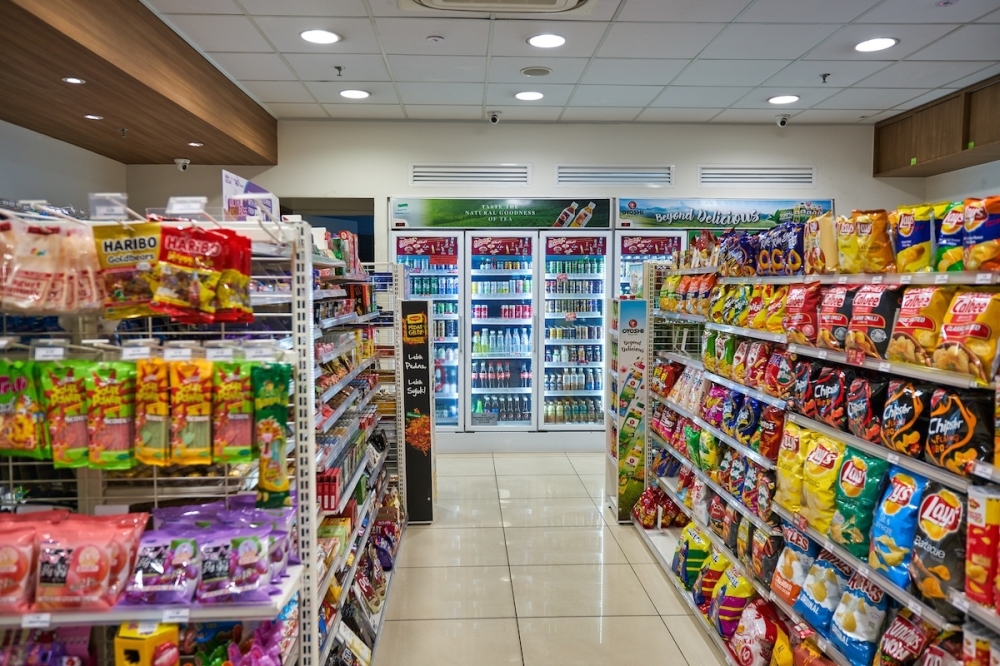 A convenience store will aisles of chips and drink coolers.