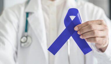 Dark blue ribbon for colon - colorectal cancer awareness on medical doctor's hand support
