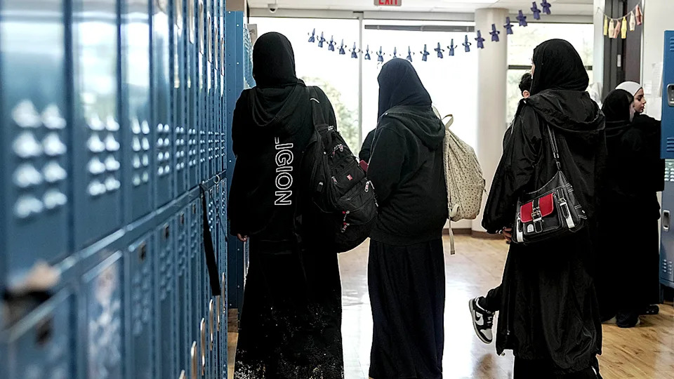 Female students in hijabs at school lockers