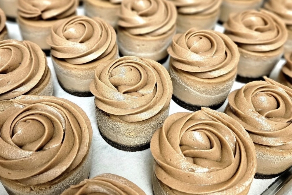 Mini chocoloate cheesecakes lined up on a sheet.