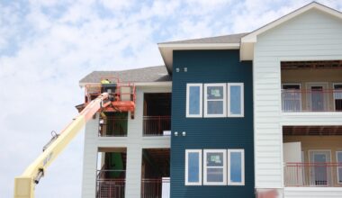 person on crane working on blue and white apartment
