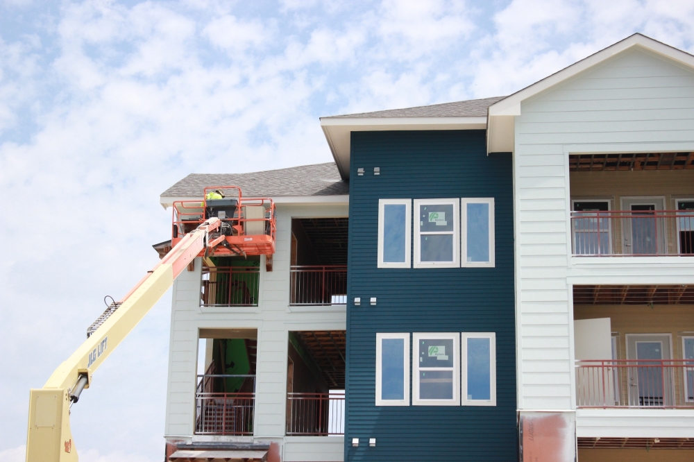 person on crane working on blue and white apartment
