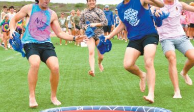 Port Aransas High School students Caden Meyer, senior, Lilly Nixon, junior, Eli Derkits, sophomore, and Julian Meyer, freshman, run to dunk a shirt in water in a relay game where participants had to get a shirt wet and run it back to the next player.