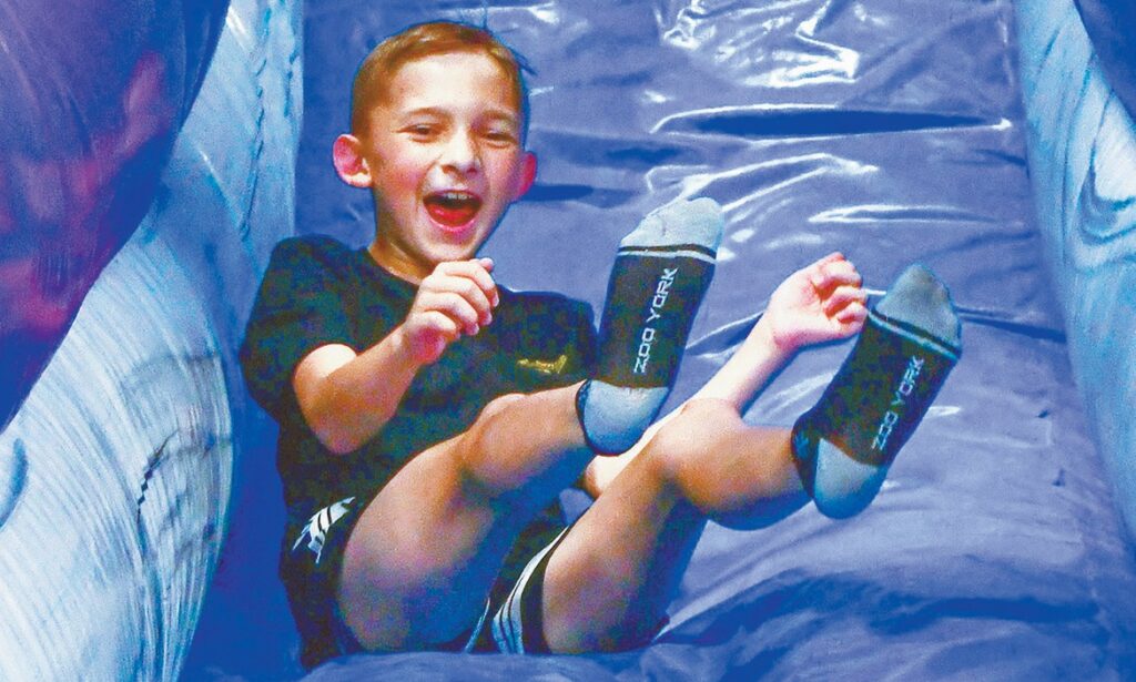 H.G. Olsen Elementary fifth grader Frazier Sullivan slides out of an inflatable slide in the school gym.