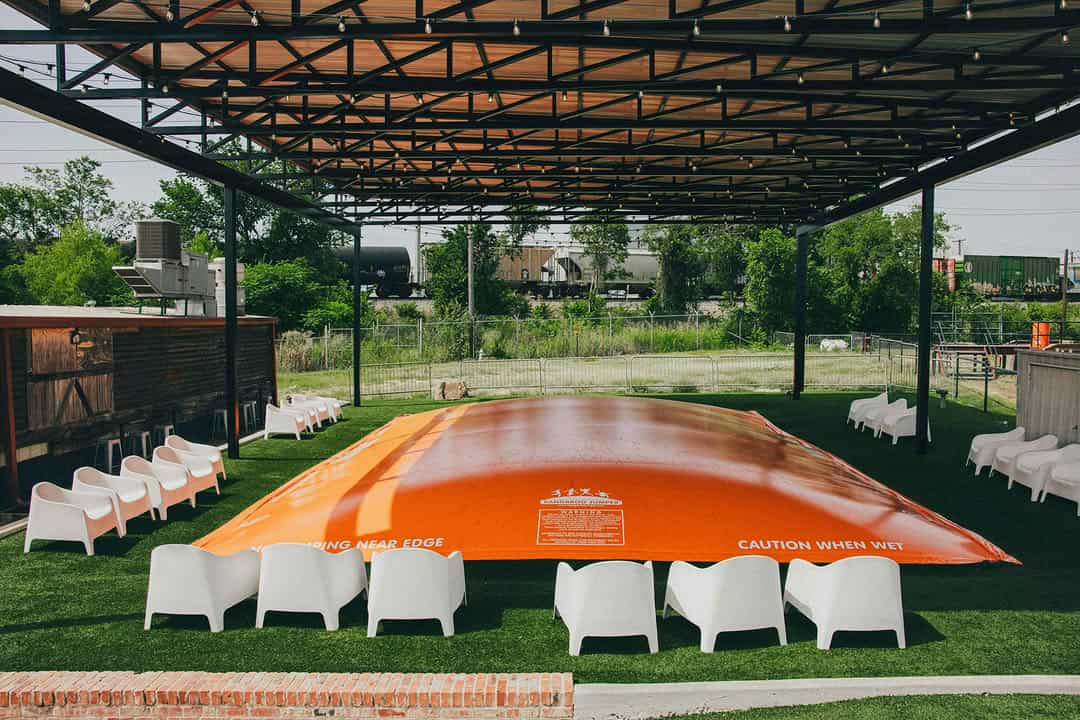 Large orange inflatable bounce, set up outdoors at a family friendly restaurant and beer garden