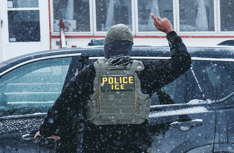An immigration and Customs Enforcement (ICE) agent raises a finger moments after detaining a man during an immigration raid, on Sunday in Minneapolis.