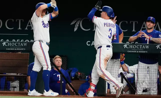 Texas Rangers' Josh Jung, left, and Joc Pederson (3) celebrate after Pederson hit a solo home run in the eighth inning of a baseball game against the Houston Astros Wednesday, May 27, 2026, in Arlington, Texas. (AP Photo/Tony Gutierrez)