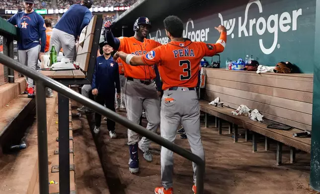 Houston Astros' Yordan Alvarez, left, and Jeremy Pena (3) celebrate in the dugout after Alvarez hit a solo home run in the eighth inning of a baseball game against the Texas Rangers Wednesday, May 27, 2026, in Arlington, Texas. (AP Photo/Tony Gutierrez)