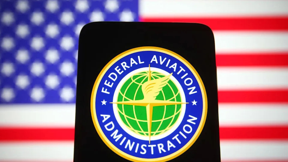 <div>UKRAINE - 2021/10/22: In this photo illustration a Federal Aviation Administration (FAA) seal is seen on a smartphone screen with the U.S. flag in the background. (Photo Illustration by Pavlo Gonchar/SOPA Images/LightRocket via Getty Images)</div>