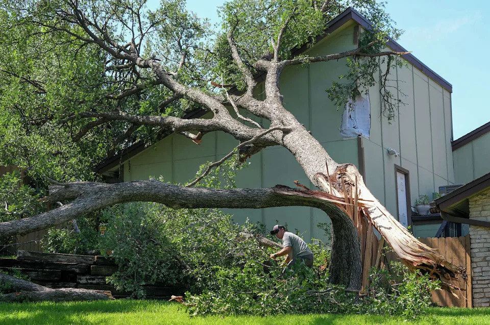 Chico Trujillo, owner of Chico’s Tree Love & Care, on Monday removes a snapped tree that damaged a house at the Timber Ridge townhomes on Timber Ridge Drive in Austin after a storm moved through the area Sunday night. (Jay Janner/Austin American-Statesman)