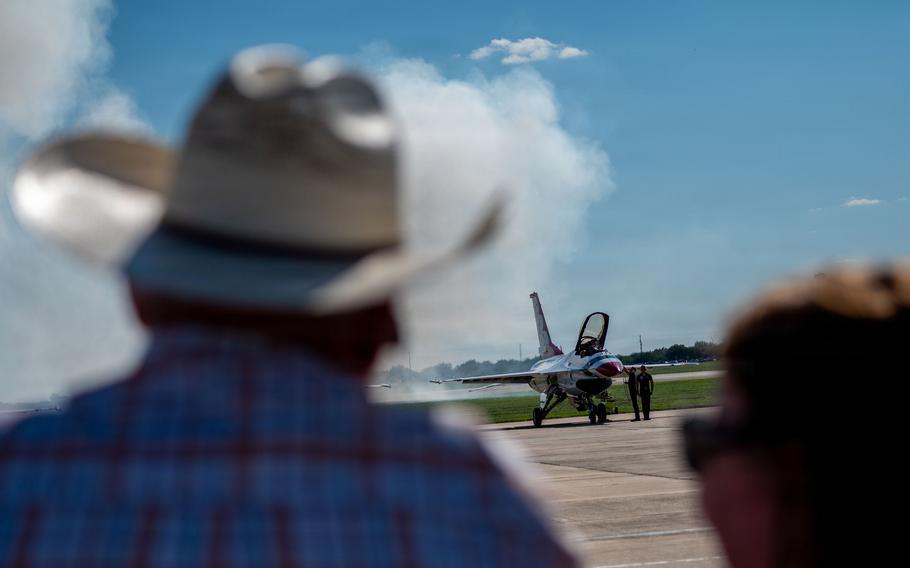 A man in a cowboy hat watches an airplane on the ground.