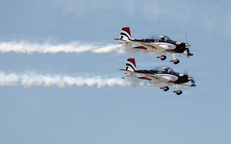 Two aircraft fly together and leave contrails behind them.