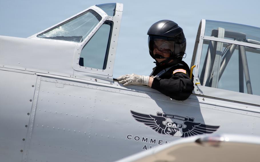 A pilot sits in an aircraft and looks to the side.