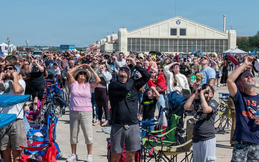 A crowd of people look up at the sky.