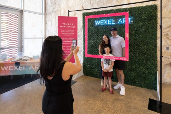 A family of three has a picture taken in a selfie booth at an art fair.