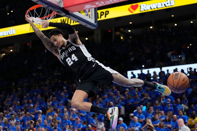 San Antonio Spurs guard Devin Vassell hangs on the rim after a dunk against the Oklahoma City Thunder during the second half of Game 7 of the Western Conference finals of the NBA basketball playoffs series, Saturday, May 30, 2026, in Oklahoma City. (AP Photo/Tony Gutierrez)