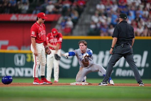 Cubs second baseman Nico Hoerner, center, reacts after reaching second base on an error by Rangers second baseman Justin Foscue, left, during the seventh inning Friday, May 8, 2026, in Arlington, Texas. (Julio Cortez/AP)