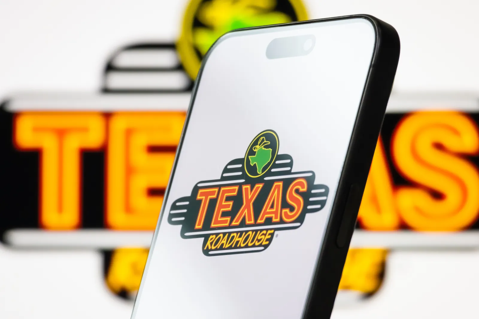 In this photo illustration, the logo of Texas Roadhouse Inc. is displayed on a smartphone screen, with the company's branding visible in the background, on May 06, 2025, in Chongqing, China.