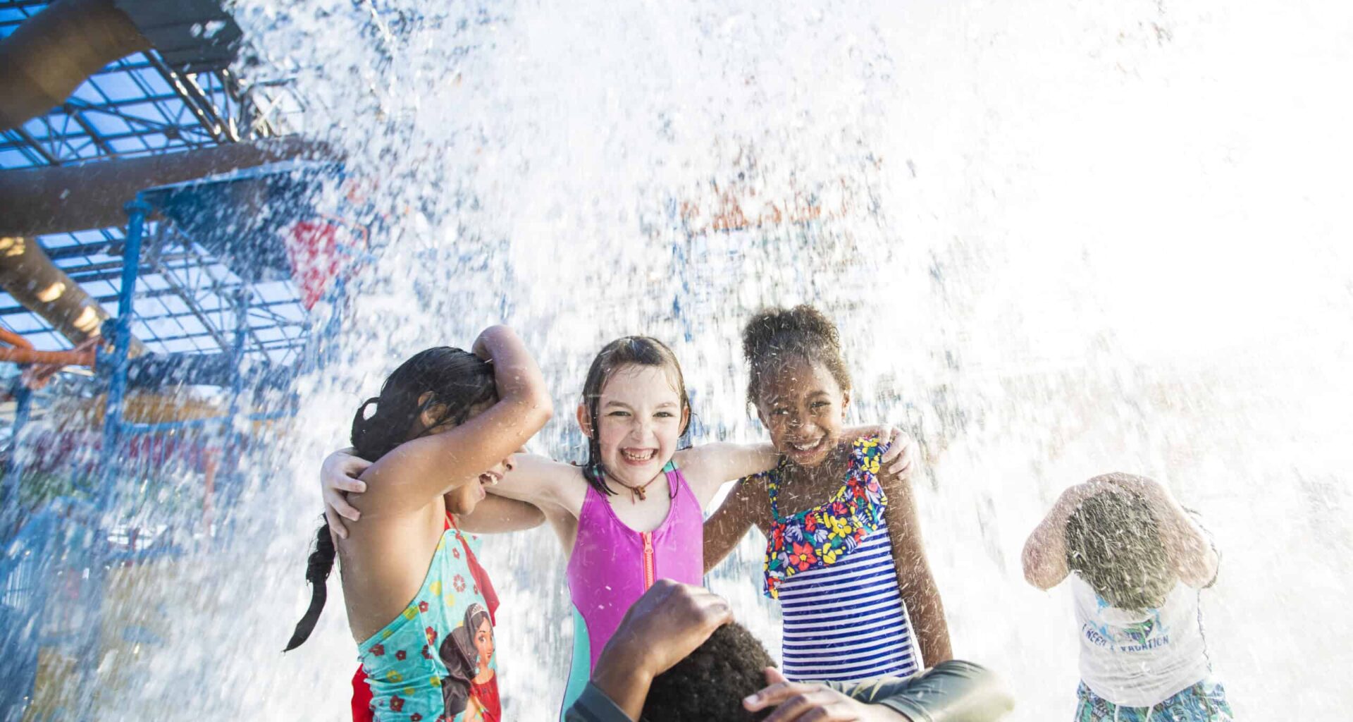 Kids playing and laughing under water spray at DFW water park.