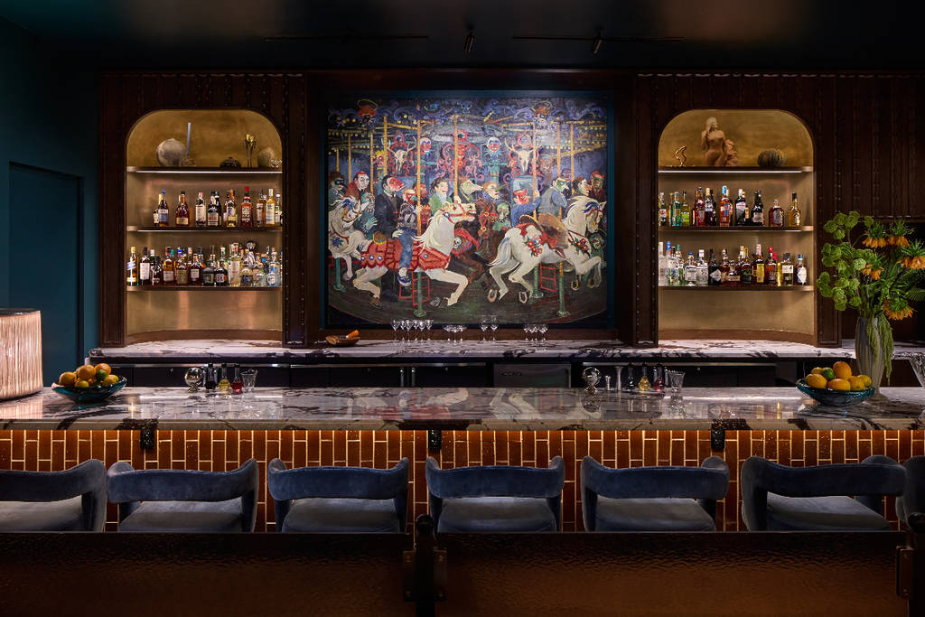 Image shows the bar area at Bar Daphne in Houston with a painting in the background. 