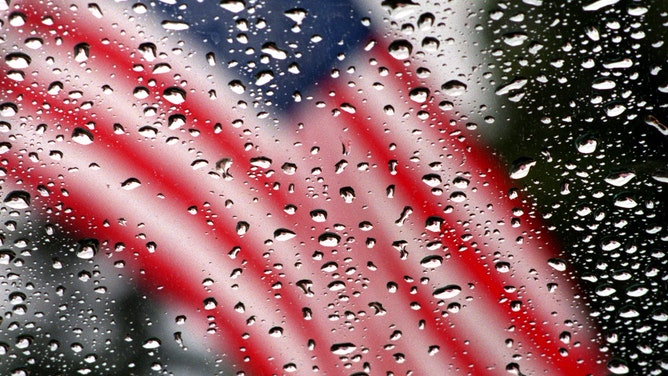 Raindrops on a windshield are seen with a flag that hangs on Carlson Building Supply in TO.