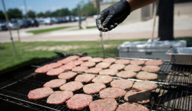 Burgers on a grill being seasoned