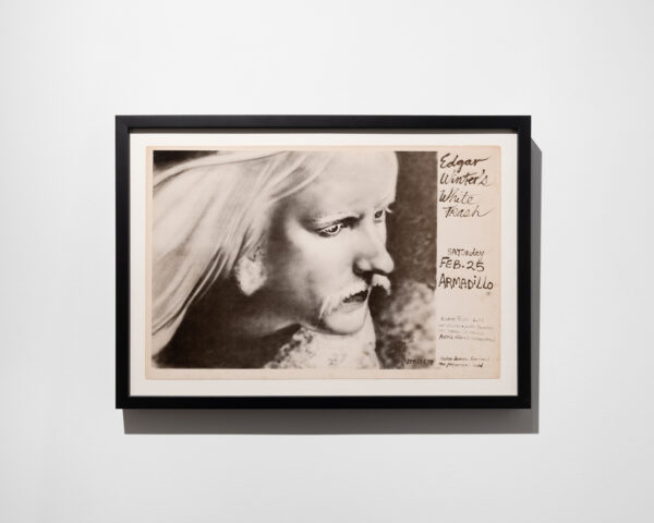 A framed concert poster featuring a figure and handwritten text.
