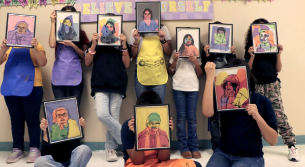 A photograph of a group of kids holding self-portraits in front of their faces.