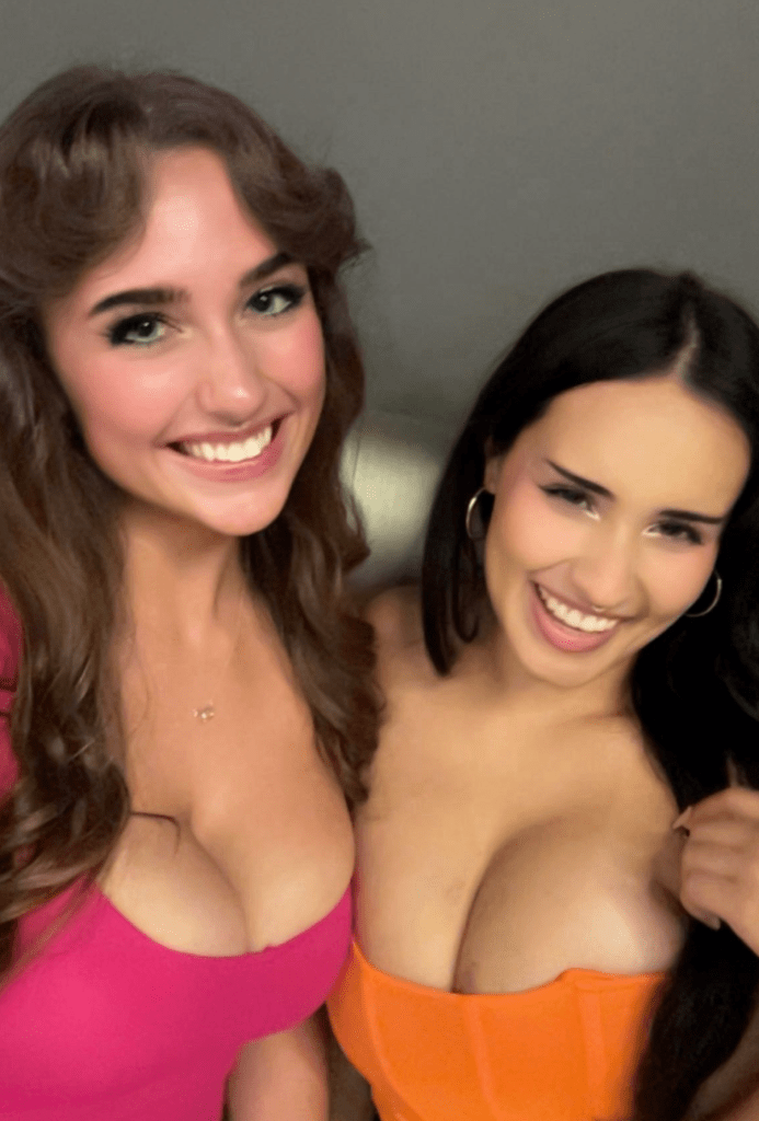 Two smiling women, one in a pink top and one in an orange top, pose for a photo.