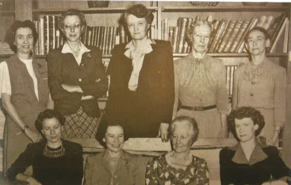 A sepia toned photograph from 1944 of a group of women professors in front of a bookshelf.
