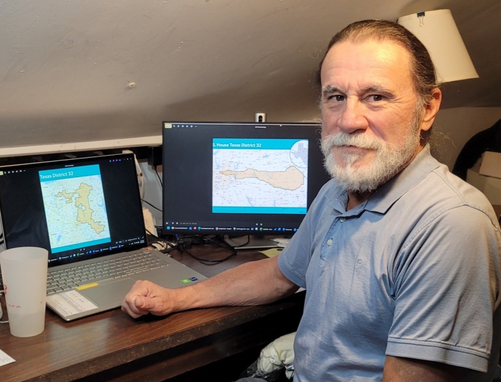 Jose Velasco sitting at desk with congressional map in background.