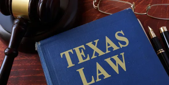 Blue book with gold text reading "Texas law" next to gavel and glasses on wood surface; An Overview of Shaw v. Simpson in Corpus Christi, Texas